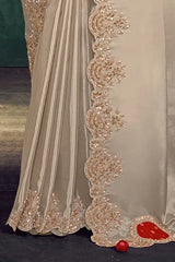 Cream silk saree with ornate gold embroidered border and scalloped lace trim.