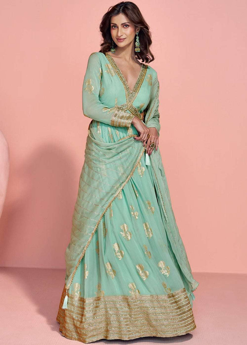 Mint green jacquard gown with gold V-neck, long sleeves, wrap-style drape, flared hem.