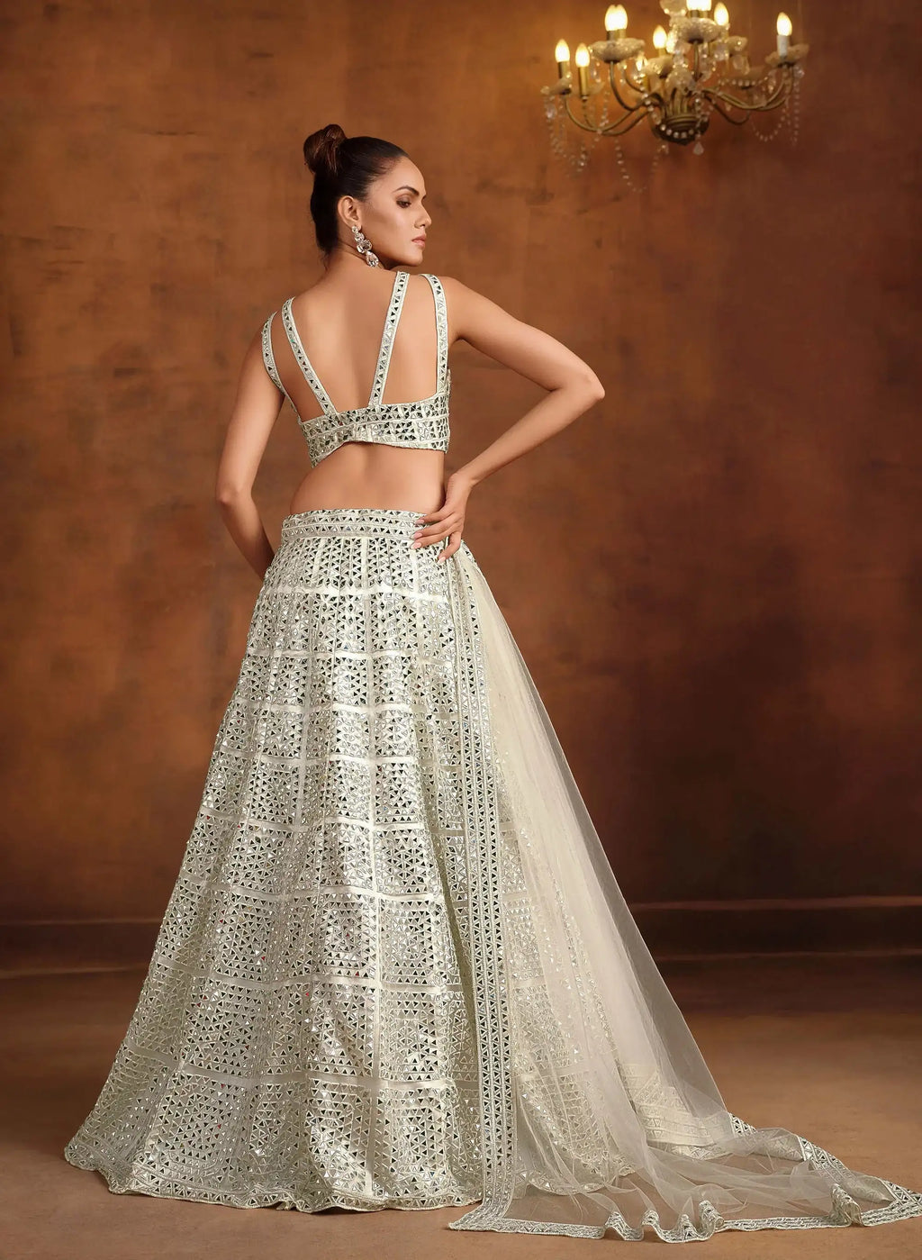 Off-white bridal lehenga with mirror-work back, tiered skirt, and sheer veil dupatta