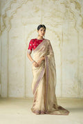 Woman wearing beige silk saree with pink sequin embroidery and red blouse in vintage setting