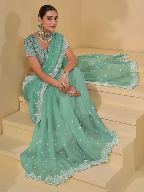 Sea green saree with white lace border, small allover motifs, and draped pallu