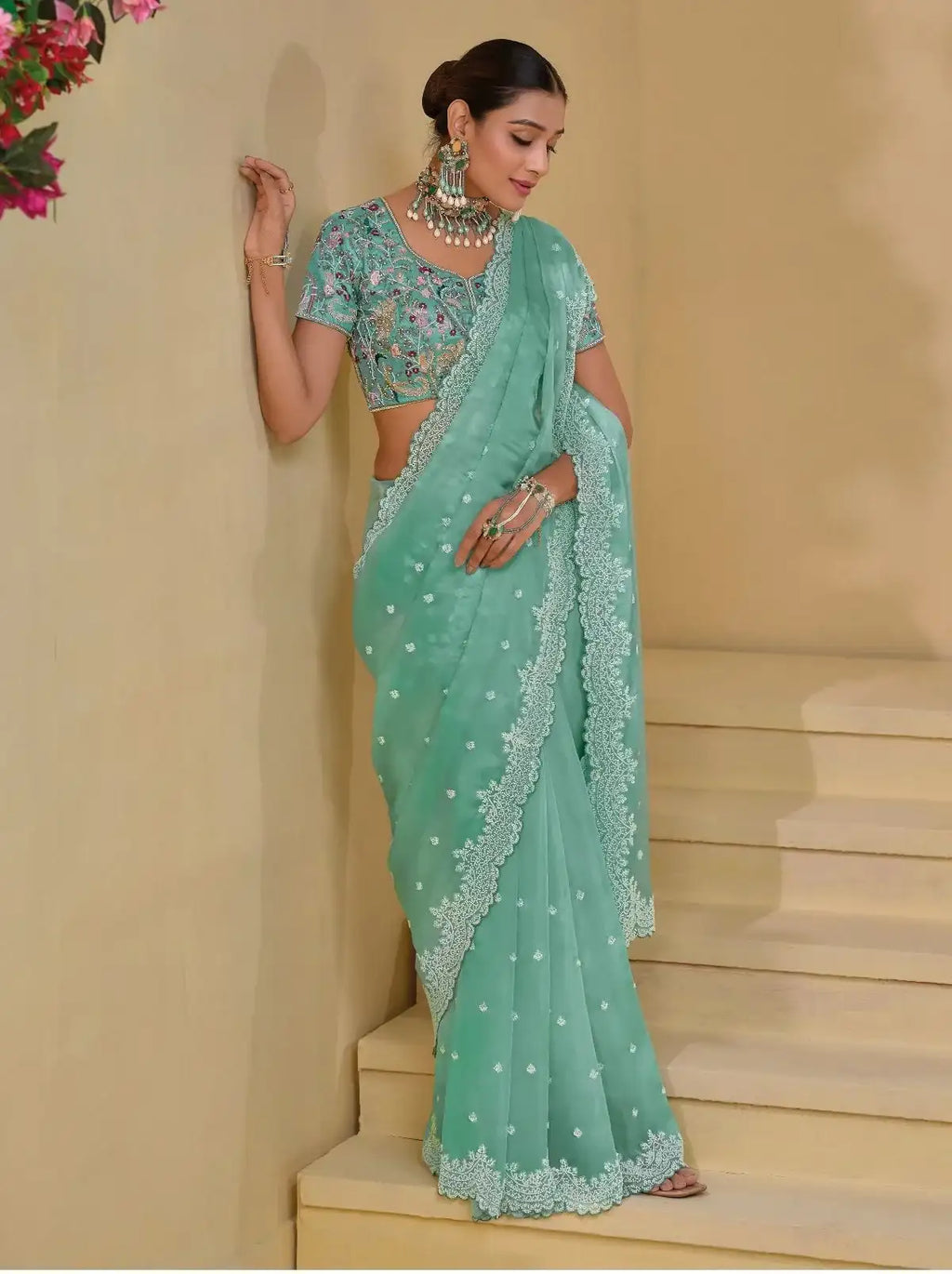 Sea green Banarasi saree with scattered motifs and lace border, angled drape.