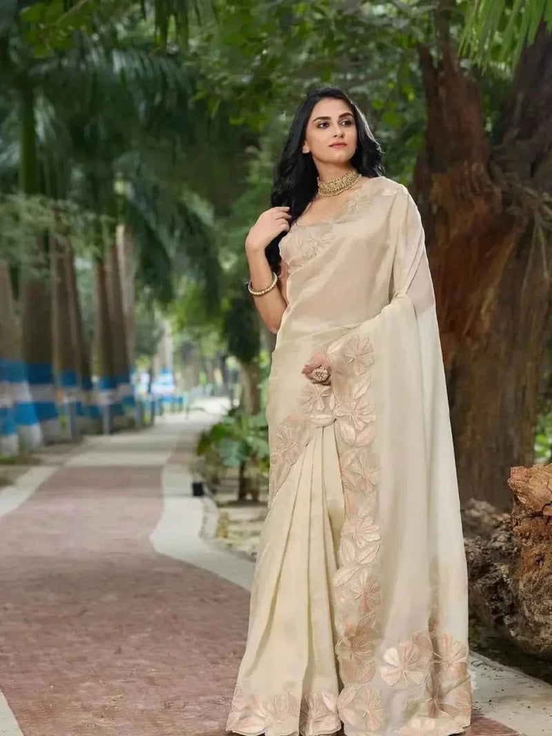 Cream organza saree with gold sequin and cutwork-style floral border at hem