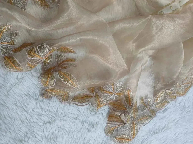 Close-up of cream organza fabric with gold sequin floral embroidery and cutwork