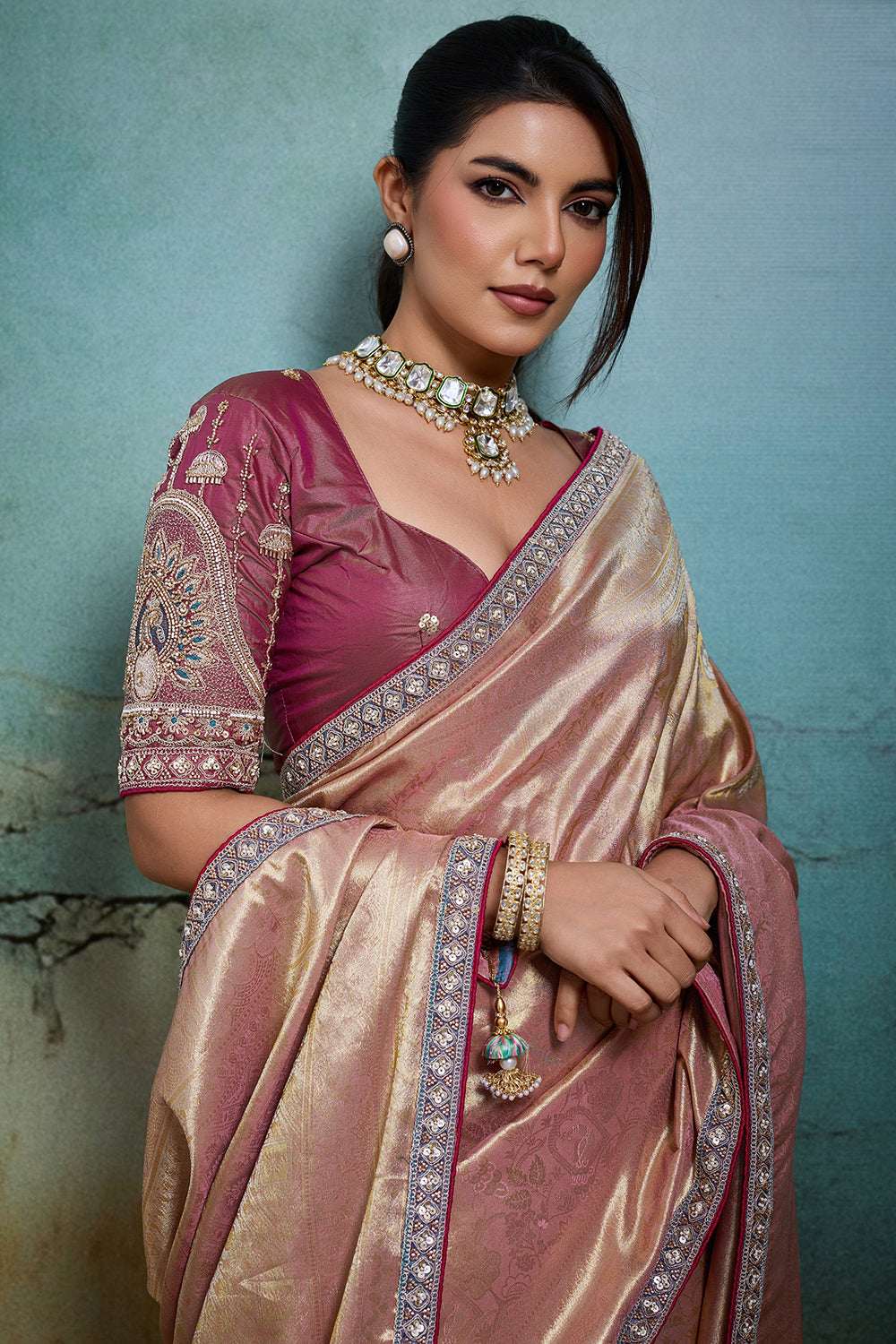 Rose-gold metallic saree draped over shoulder with dark maroon embellished border