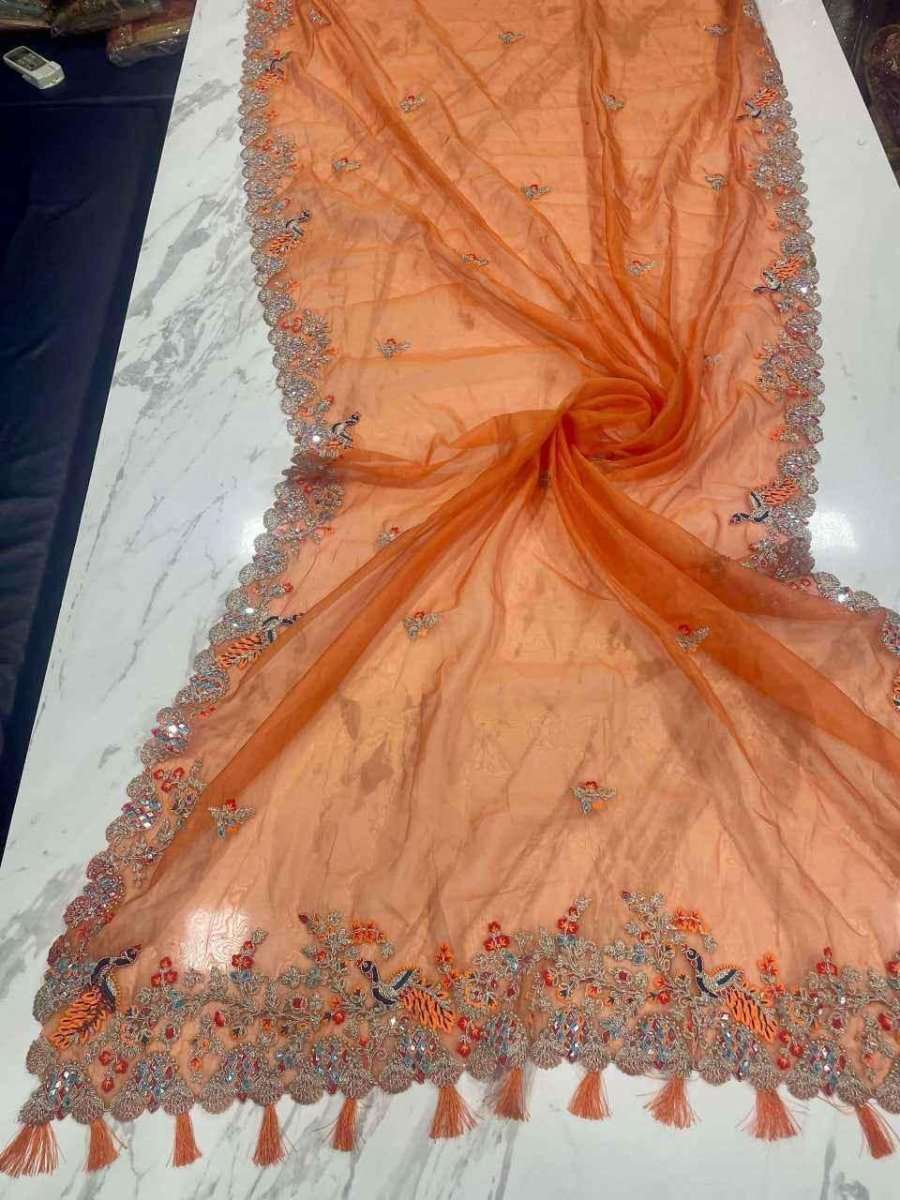Organza mirror saree draped flat, orange fabric with embellished silver border and tassels