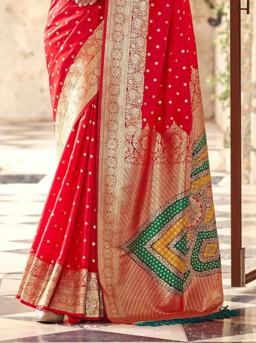 Crimson red silk saree with cream-gold panel, green geometric border, and embellished hem