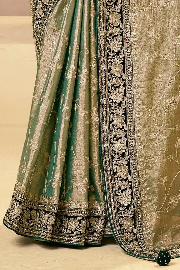 Green pleated saree with gold zari hem and ornate navy border trim