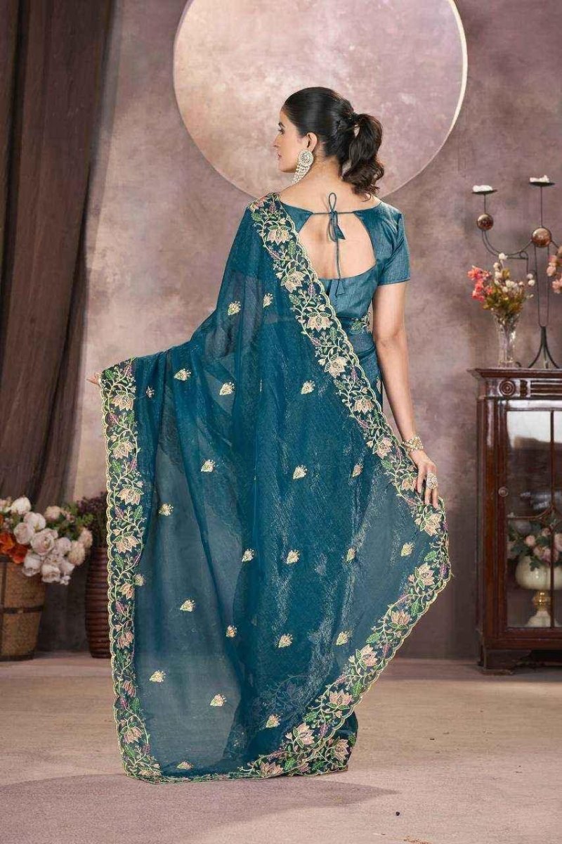 Back view of teal embroidered saree with gold border and short-sleeve blouse.