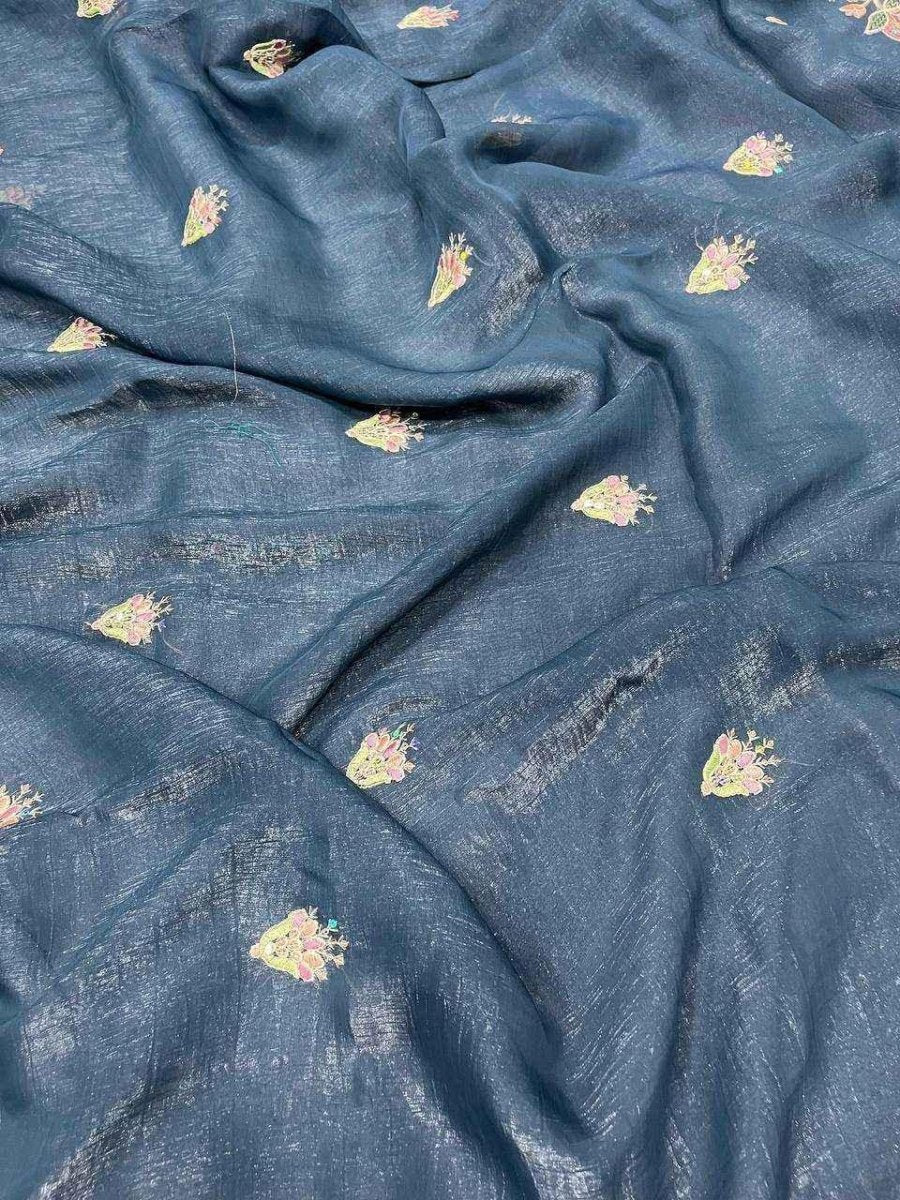 Teal saree fabric with scattered small pastel motifs and subtle sheen.