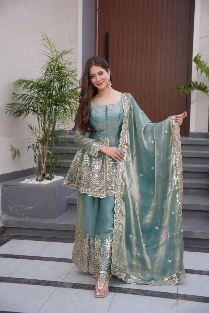 Teal satin sharara suit with mirror embroidery and gold border, dupatta draped over shoulders