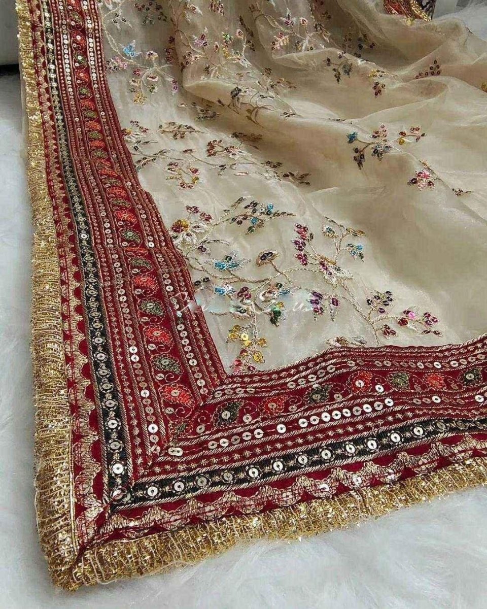 Cream organza saree corner with maroon border, gold trim, and tiny multicolor florals