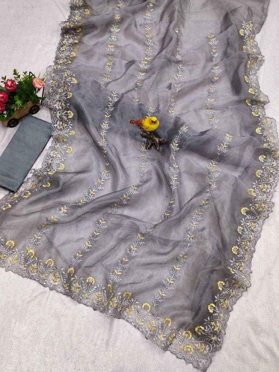 Grey organza saree with wide embroidered border and yellow floral vines, draped flat
