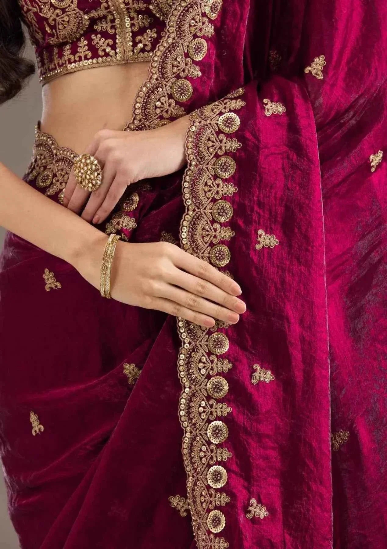 Close-up of woman wearing hot pink satin silk saree with heavy gold jari cutwork embroidery and matching jewelry