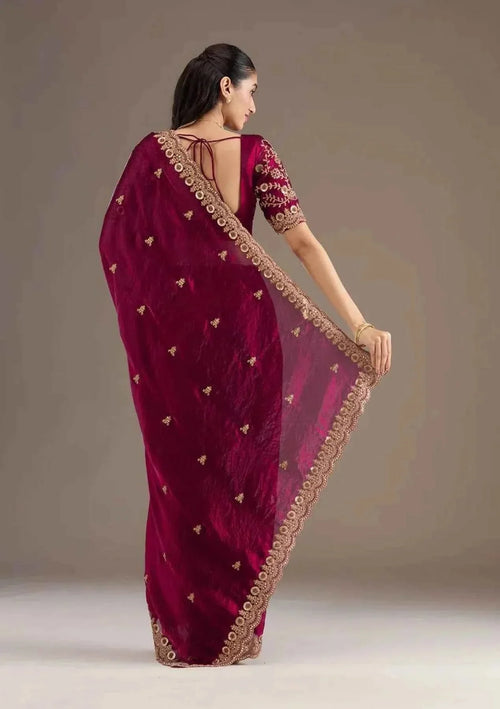 Woman wearing maroon silk saree with heavy jari embroidery and cutwork, back view