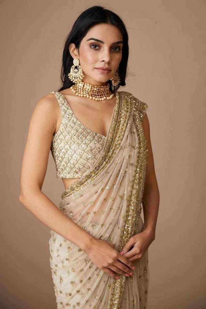 Ivory and gold sequin net saree with draped pallu and gold border detail, worn on model