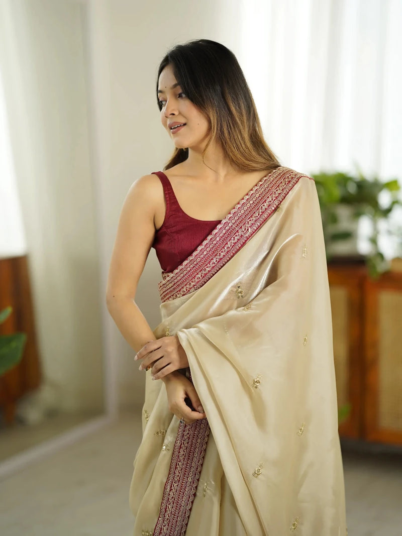 Ivory satin silk saree with pink sequin-trimmed diagonal border and draped pallu
