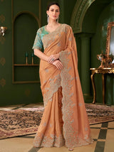 Embroidered burnt orange georgette saree with teal blouse, ornate silver accents