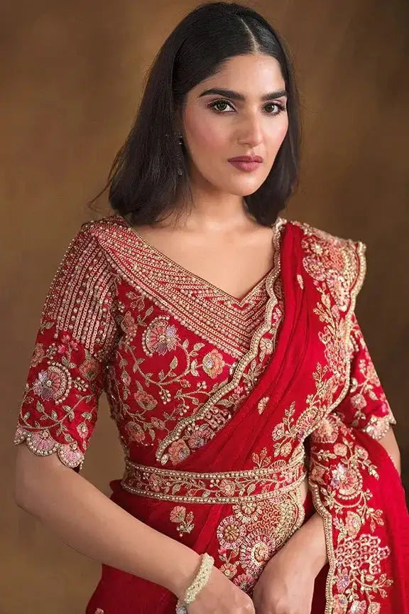Cherry red silk saree with gold embroidery and draped red pallu, worn with belt