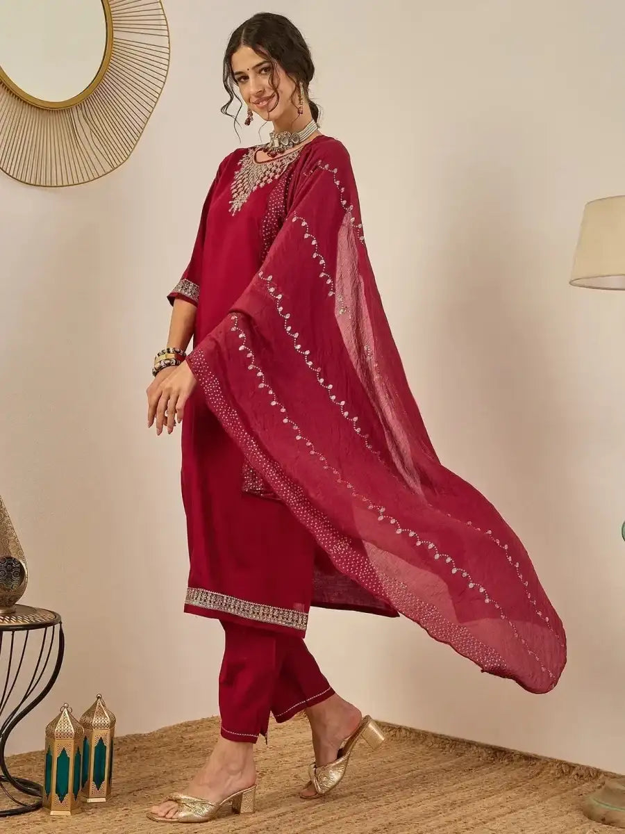 Deep maroon embroidered kurta suit set with embellished dupatta flowing over arm