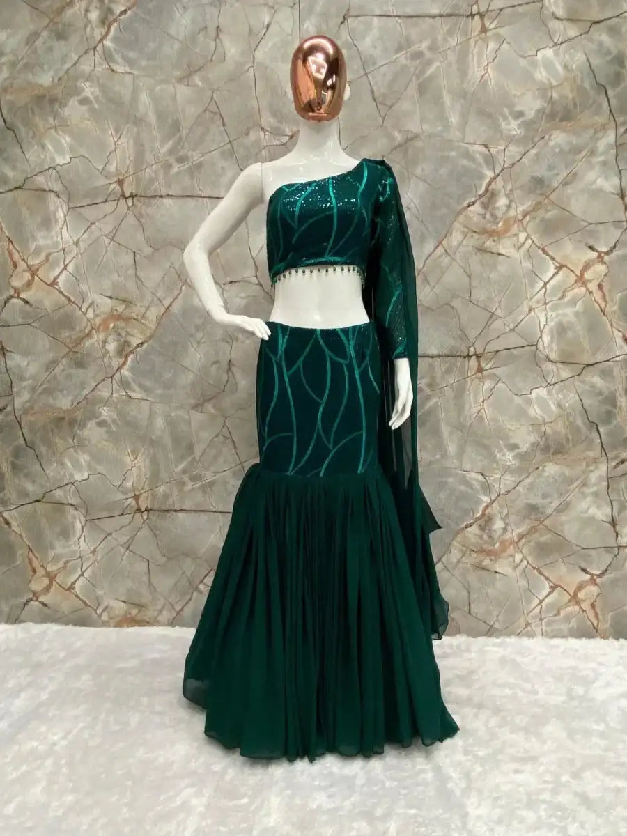 Emerald green lehenga set on mannequin with cropped top and tiered skirt