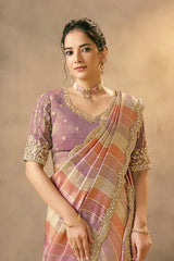 Pastel silk saree drape with metallic multi-stripe pattern and gold-embellished neckline