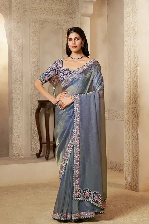 Blue tissue silk saree with pink floral embroidery and decorative border, draped
