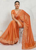 Orange metallic shimmer chiffon saree with gold floral and geometric border, draped