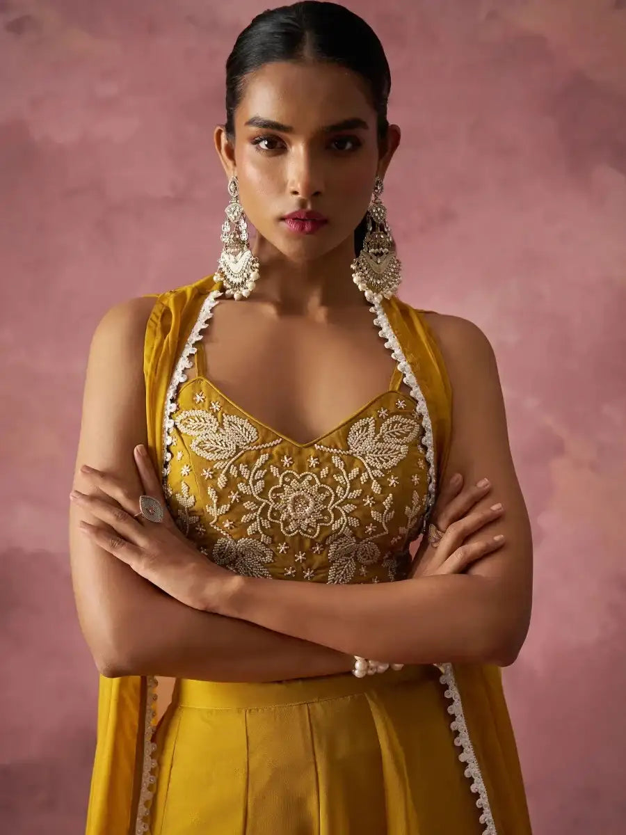 Mustard yellow sharara set close-up of gold embroidered bralette and cape trim