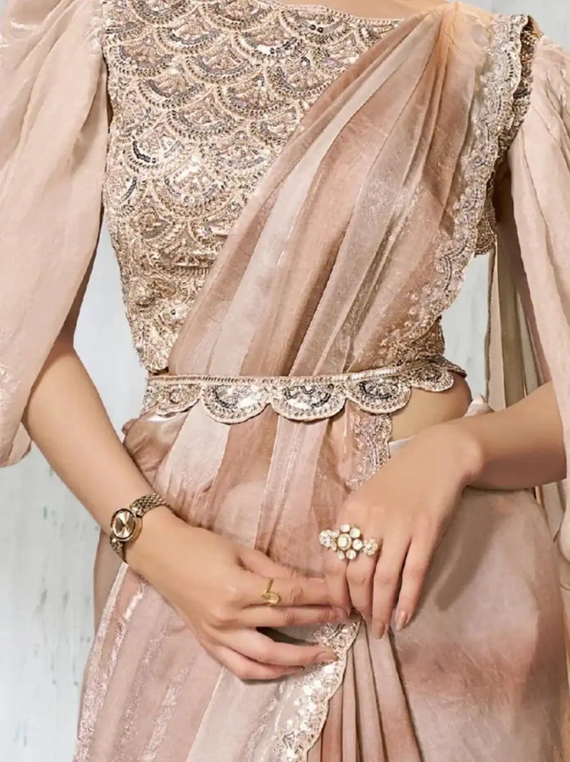 Rose gold metallic saree close-up: embroidered bodice, jeweled waist belt, pleated skirt.