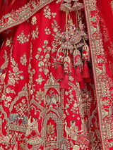 Close-up of crimson bridal lehenga fabric with intricate gold embroidery and tassel trim