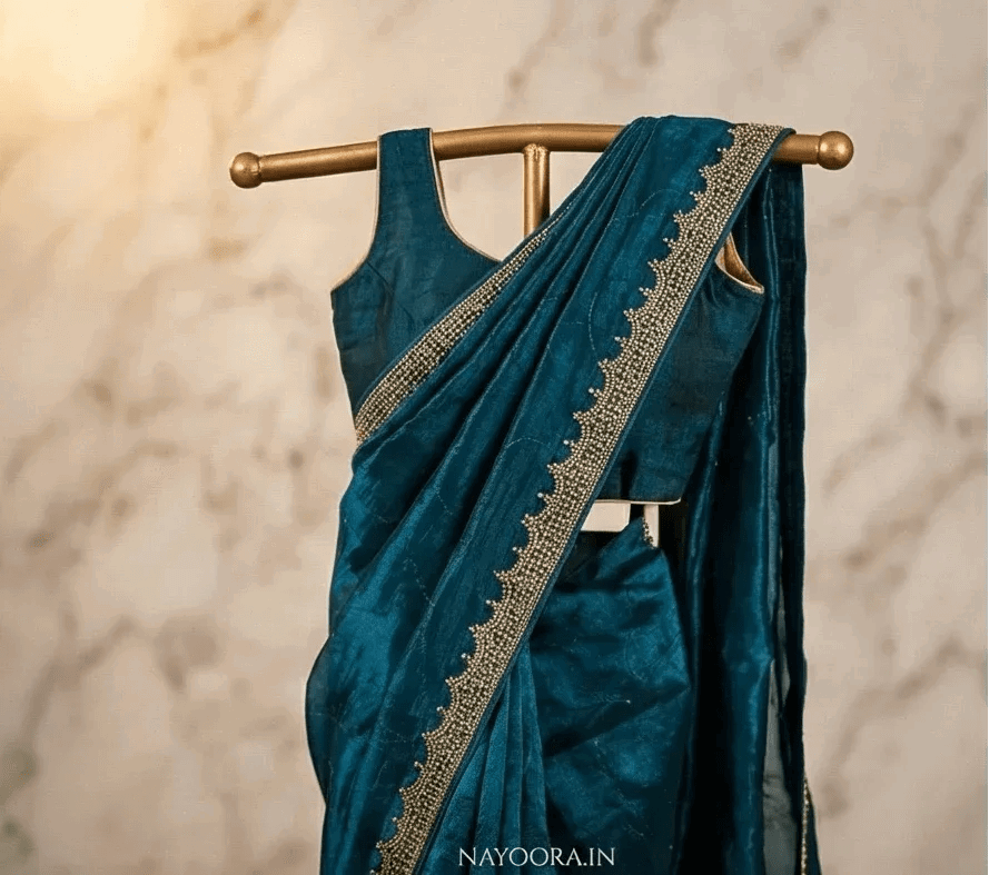 Deep teal blue saree with gold-toned stone border and draped pleated body