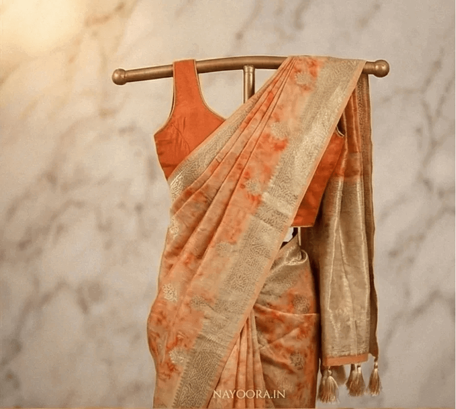 Peach shibori printed saree with wide gold border and tassel trim