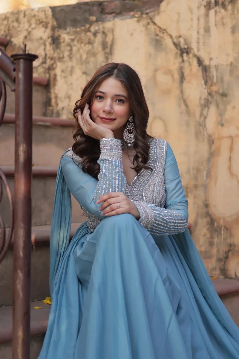 Blue embroidered gown with sequined yoke, long sleeves, and layered skirt