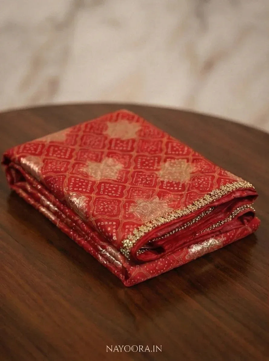 Red bandhani georgette saree folded, patterned body with gold embellished border