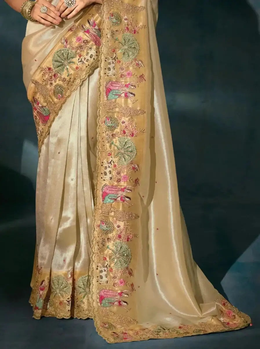Golden cream saree with ornate border and colorful embroidery on pallu and hem