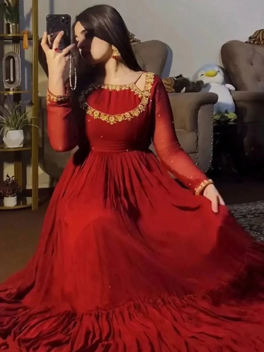 Ruby red designer flare gown with gold trim, long sleeves, flowing skirt from back view