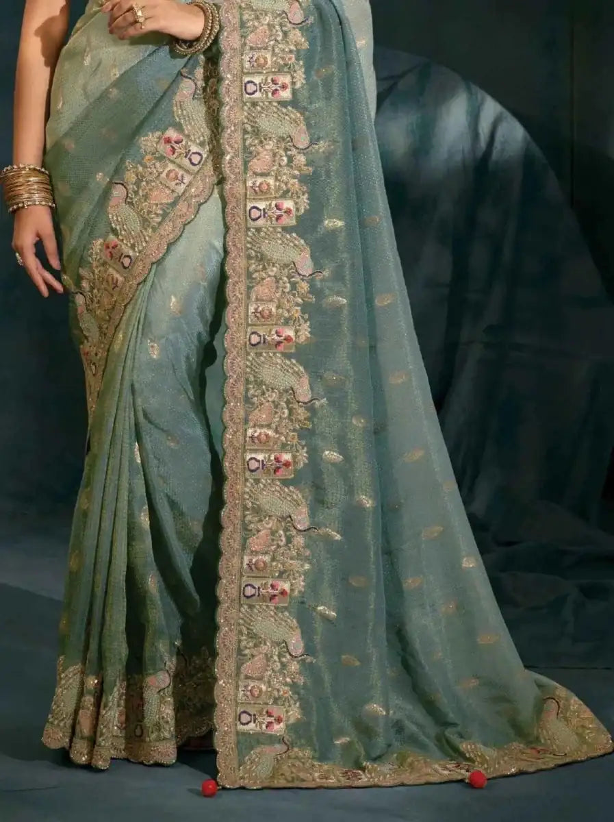 Sage green silk saree with ornate vertical border and gold motifs along the pleats