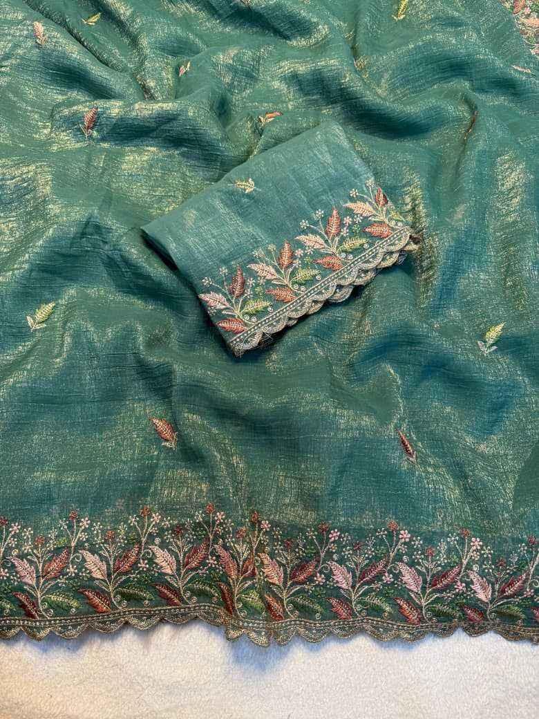 Teal green fabric close-up with scattered gold motifs and floral embroidered border