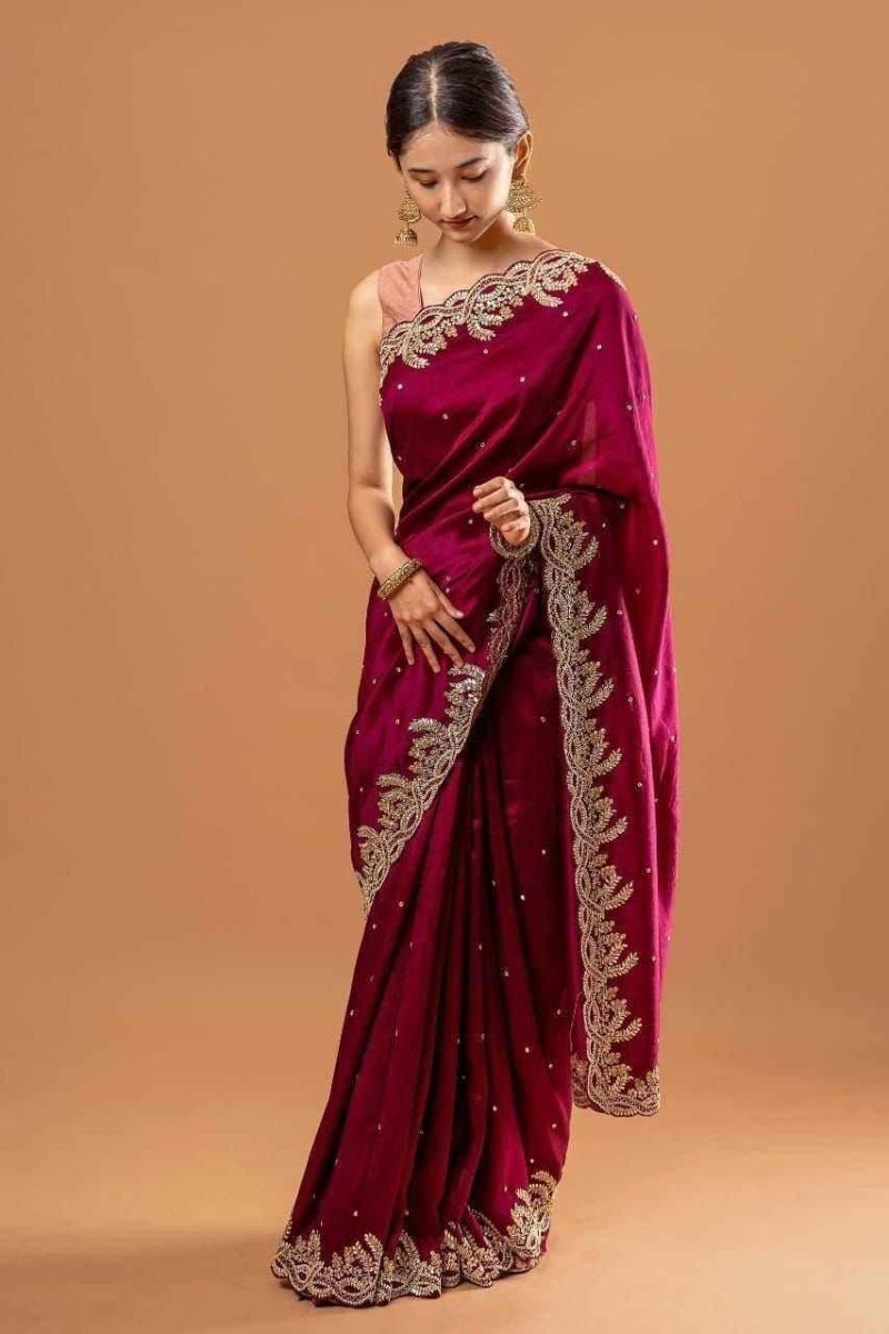 Wine silk saree with gold zari and sequin cutwork border, draped with ornate pallu