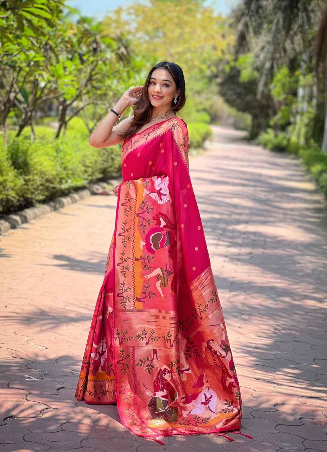 Woman wearing rani pink Paithani silk saree with intricate zari weaving and traditional artwork outdoors