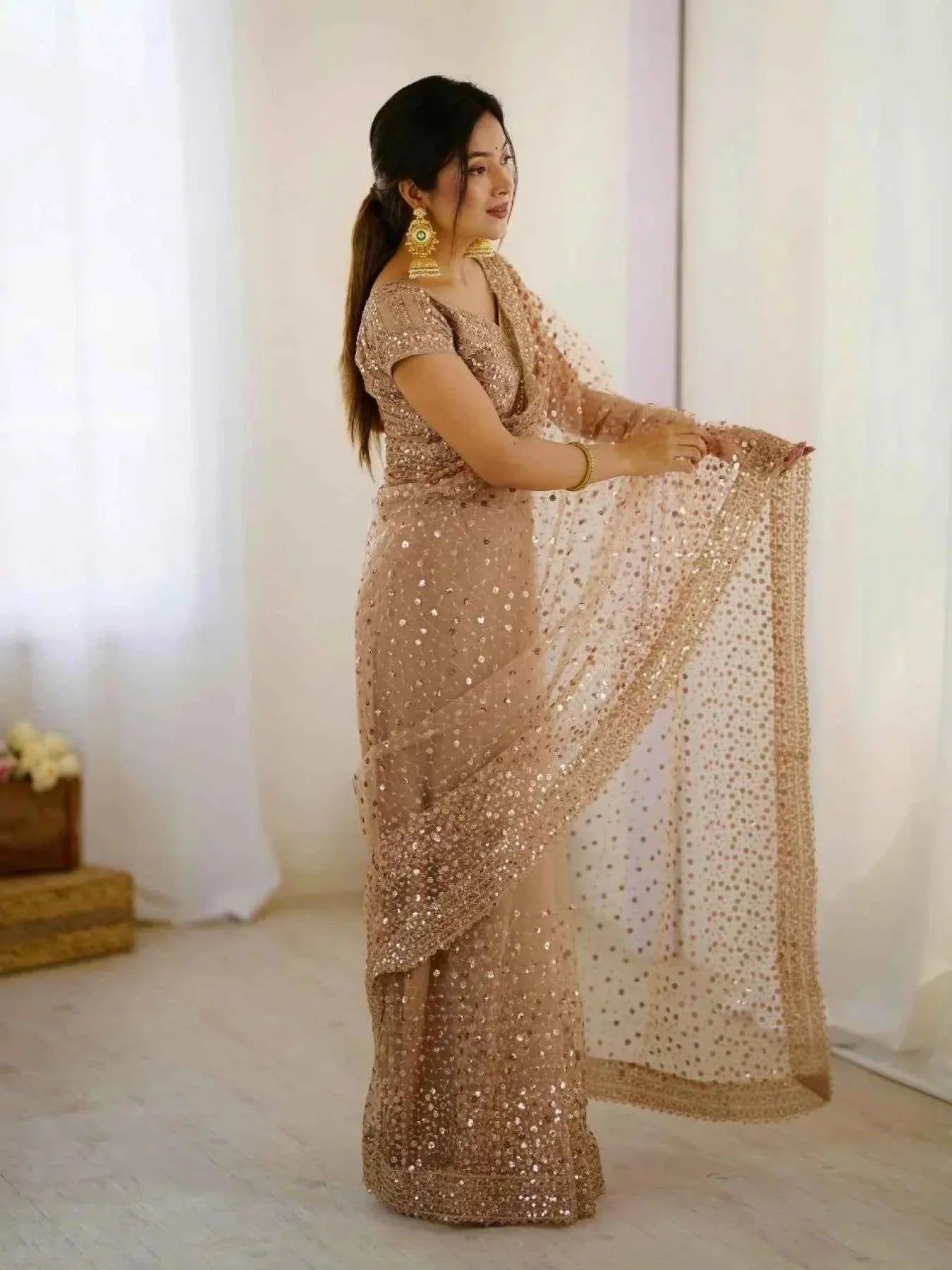 Woman in rose gold net saree with all-over sequin embroidery and matching blouse indoor