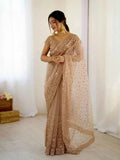 Woman wearing rose gold net saree with all over sequin and dori embroidery, posing indoors