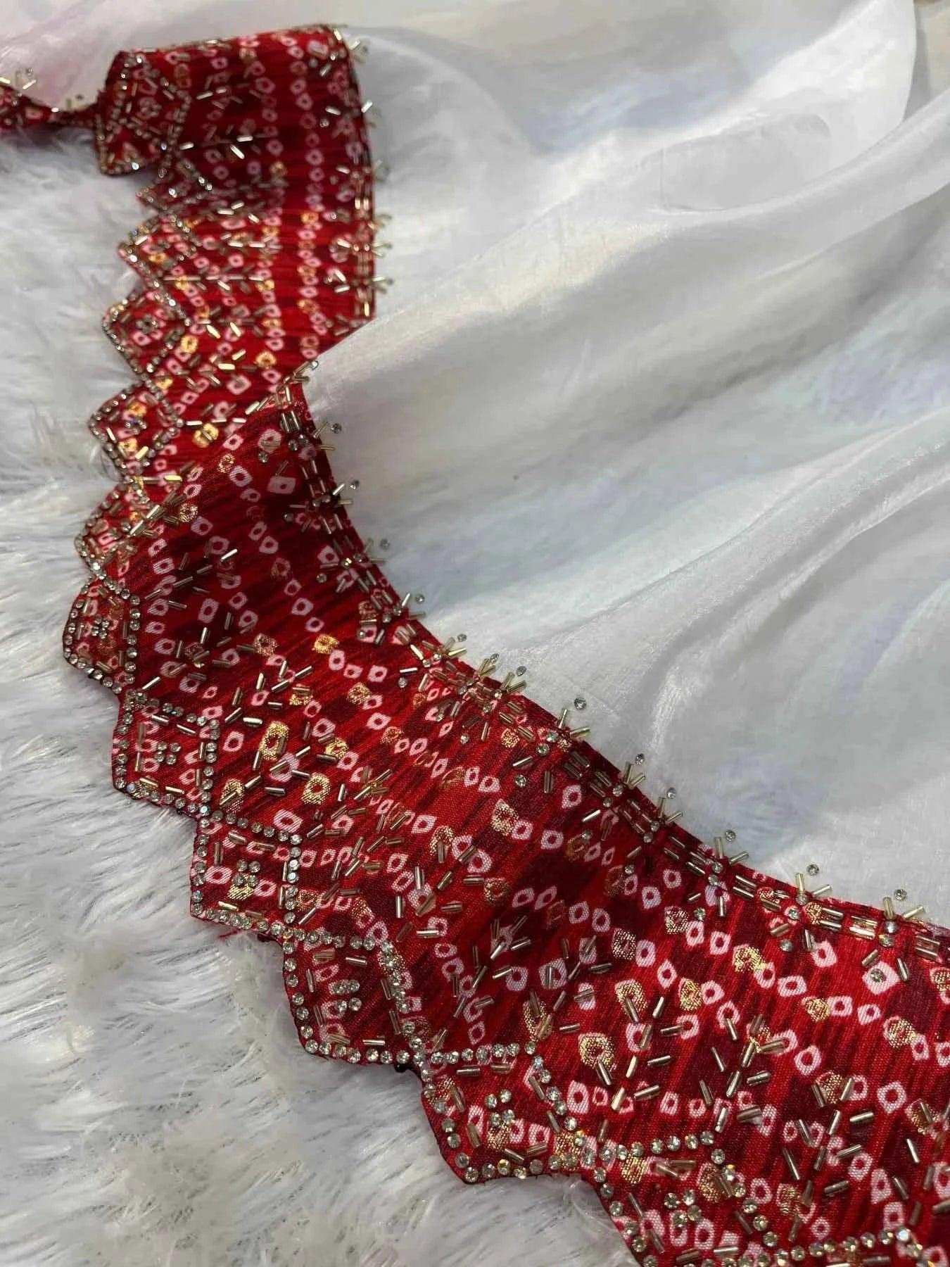 White tissue saree draped over soft surface with red Bandhani blouse embellished with beads