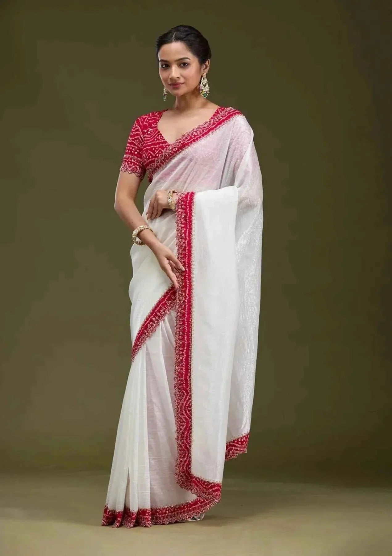 Woman wearing elegant white tissue saree with red embroidered border and red Bandhani blouse