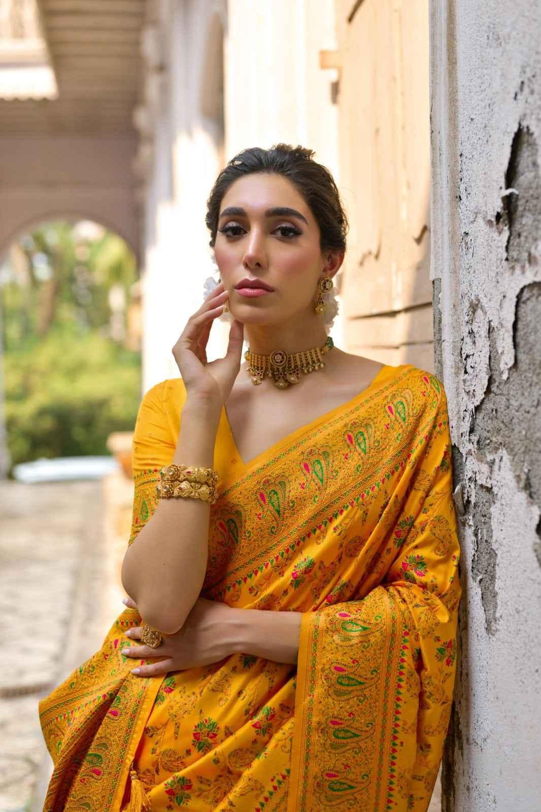 woman wearing yellow pashmina silk saree with traditional Kashmiri jal weaving and gold jewelry